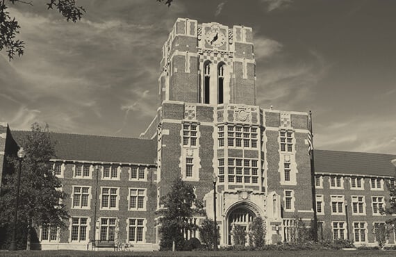 A historic brick university building with a clock tower, shown in sepia tone.